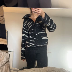 teddyjacka zebramönster h&m - Säljer en mysig svart och vit fleecejacka med zebramönster. Jackan har dragkedja framtill och långa ärmar. Perfekt för kyliga dagar!