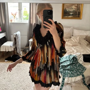 Färgglad miniklänning - Säljer en unik och färgglad miniklänning från Lindi med ett abstrakt mönster i svart, orange, rosa och gult. Klänningen har volangdetaljer vid halsringningen och ärmsluten, samt trekvartsärmar. Perfekt festlig klänning till sommaren eller när man ska på semester😍