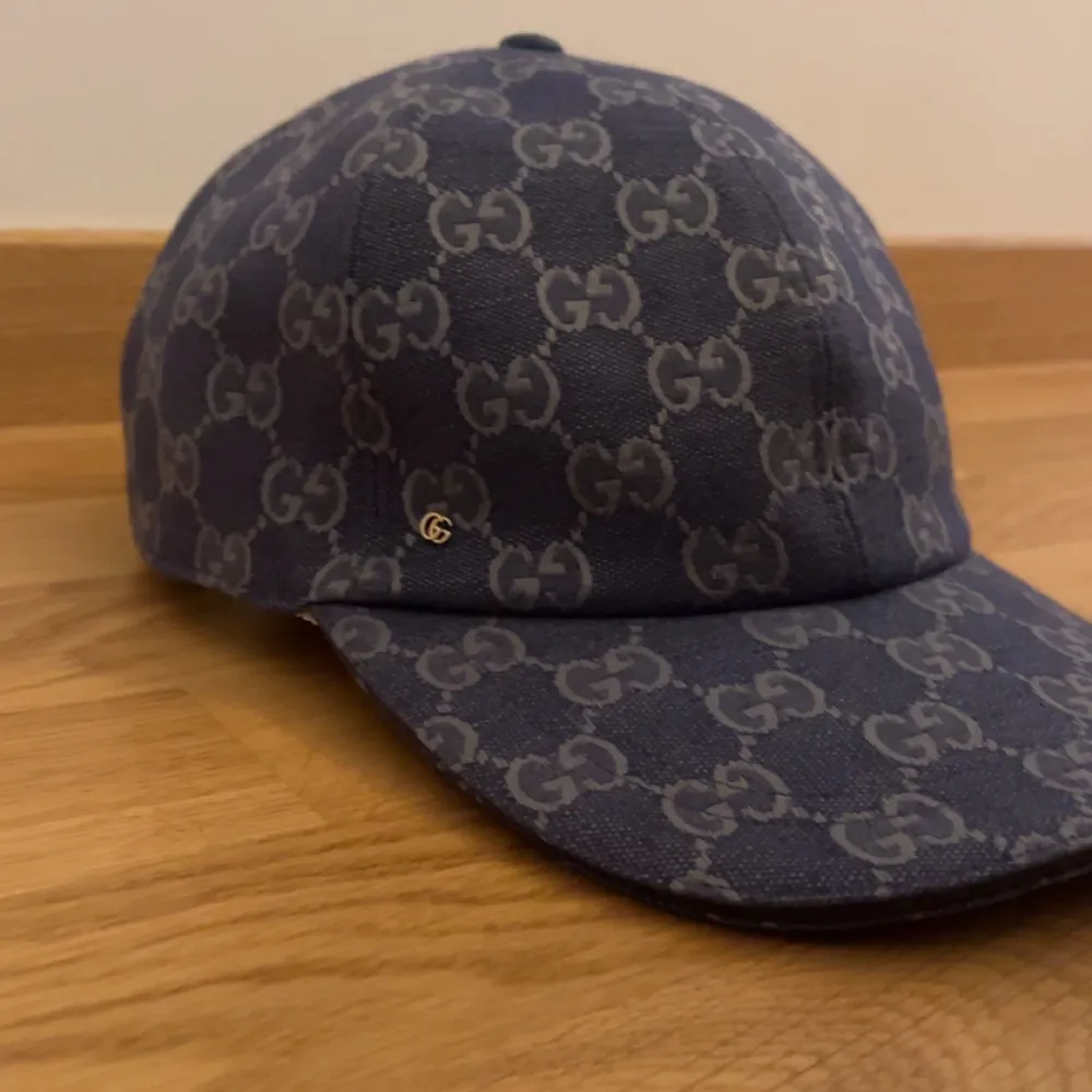 Snygg blå keps från Gucci med det ikoniska GG-mönstret i grått. Kepsen har en klassisk design med böjd skärm och justerbar passform. Perfekt för att ge din outfit en lyxig touch.. Asusteet.