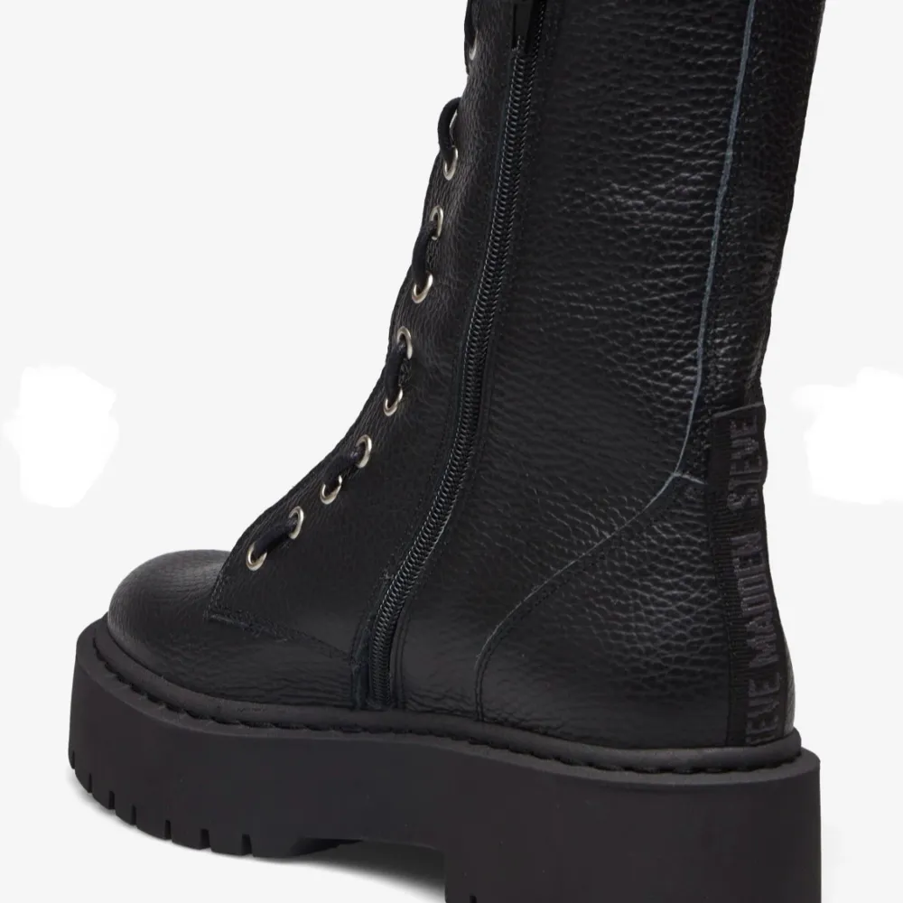 Snygga svarta boots i skinn med både snörning och dragkedja för enkel på- och avtagning. De har en robust platåsula som ger extra höjd och stil. Perfekta för en edgy look.. Kengät.