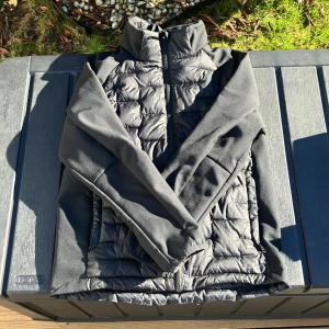 Svart cardigan från Everest - Säljer en svart cardigan från Everest med dragkedja. Jackan har en quiltad design och långa ärmar. Perfekt för kyligare dagar. Hör av dig vid intresse!