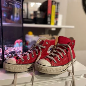 Röda Converse All Star sneakers - Säljer ett par klassiska röda Converse All Star sneakers med hög snörning och rund tå. Lite skitiga men finns inget fel på dem!
