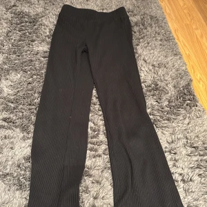 Svarta ribbade byxor från H&M - Snygga svarta ribbade byxor från H&M. De har en elastisk midja och en stilren design som passar perfekt för en avslappnad look. Byxorna är tillverkade i ett mjukt och bekvämt material.