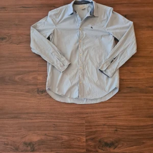 Ljusblå skjorta - Säljer en stilren ljusblå skjorta från L.O.G.G. med broderad detalj på bröstet. Storlek 170 barn