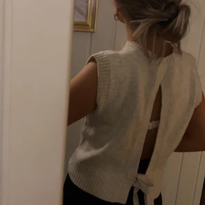 Beige stickad topp med öppen rygg och knyt - Säljer en beige stickad topp med rund halsringning och breda axlar. Toppen har öppen rygg med knytband som knyts till en rosett nedtill vilket ger en snygg detalj. Extremt lätt att styla och passar perfekt till alla tillfällen🤩(Aldrig använd då jag helt glömt bort att jag köpt den, köpte utomlands men blev aldrig använd just av den anledningen)