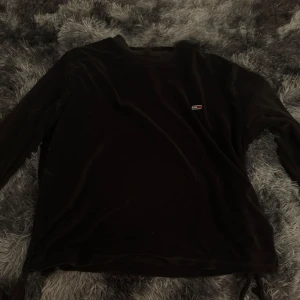 Svart tröja från Tommy Hilfiger - Säljer en svart lång armad tröja som är mjuk och är fràn Tommy Hilfiger. Tröjan har en liten logga pà bröstet och rund halsringning. Perfekt för en stilren och bekväm look. Medium storlek.