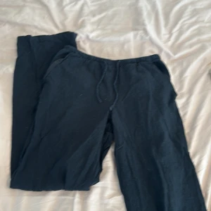 Svarta linnebyxor från Gina Tricot - Svarta linnebyxor från Gina Tricot med resår i midjan och dragsko. Byxorna har raka ben och är tillverkade i ett mjukt material som passar perfekt för en avslappnad stil.