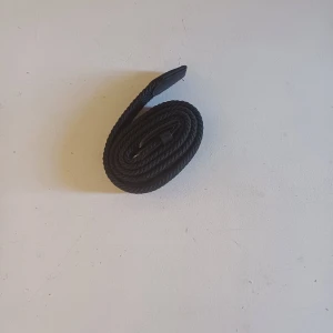 Svart flätat bälte med metallspänne - Säljer ett svart flätat bälte med längd på 80 cm. Bältet har ett klassiskt svart metallspänne och detaljer i svart konstläder. Passar perfekt till jeans eller chinos för en stilren look.