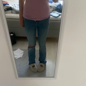 Ljusblå jeans med hål på knät - Säljer ett par ljusblå jeans med hål på ena knät. Jeansen har låg/medel midja och rak bootcut där nere. Passar inte riktigt mig därav kan bilderna vara missvisande, pria går att diskuteras! 💕