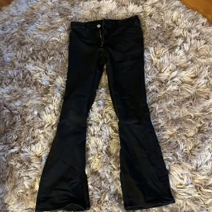 Svarta bootcut jeans💗 - Snygga svarta byxor från H&M med flared leg och justerbar midja. Byxorna har låg midja och är perfekta för en trendig look. De är tillverkade i ett material som ger en skön passform och stil. Jag har använt de tre gånger och säljer för att de är för små😭tvättar och stryker innan de skickas!! Jag köpte de för 300kr men säljer för 150-200💗Priset kan diskuteras 