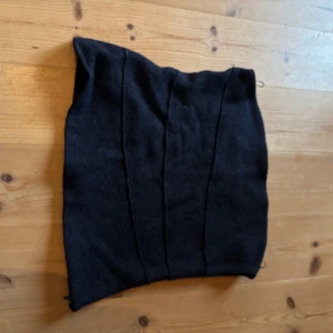 Svart kortkjol i ull - En marinblå bandeåtopp med markerade sömmar framtill. Bandeåtoppen har en enkel och stilren design och är tillverkad i ett mjukt ullmaterial. Perfekt för dig som gillar minimalistisk stil. Storlek L passar M