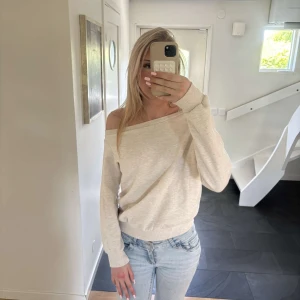 Beige offshoulder tröja - Säljer en beige offshoulder tröja i mjukt material. Tröjan har lång ärm och en avslappnad passform, perfekt att styla med jeans eller kjol. Enkel och stilren design som passar till många tillfällen.