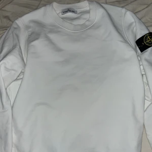 STONE ISLAND Crewnecl - Säljer en stilren vit sweatshirt från Stone Island med klassisk patch på vänster ärm. Tröjan har rund halsringning och långa ärmar. Perfekt för en clean och avslappnad look. Kvitto och orderbekräftelse finns. Använd 1 gång