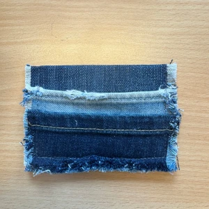 Handgjord plånbok i jeans - Unik plånbok sydd av återvunna jeansbitar med råa kanter och flera nyanser av blått. Perfekt för dig som gillar en personlig och kreativ stil. Plånboken är kompakt och får plats i fickan eller väskan.