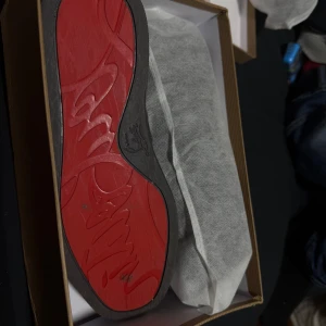 Svarta sneakers med nitar från Christian Louboutin - Säljer ett par svarta sneakers från Christian Louboutin med ikonisk röd sula och coola nitar framtill. Skorna har en chunky design och är tillverkade i skinn. Kommer med originalkartong och dustbag. Storlek 43 men passar storlek 44 också.