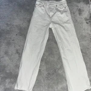Vita raka jeansbyxor - Säljer ett par vita jeansbyxor med raka ben och klassisk femficksdesign. Byxorna har normal passform och är perfekta för en clean och fräsch look. Passar till många olika stilar och tillfällen. Storlek 42 & är använd endast vid ett tillfälle 😊