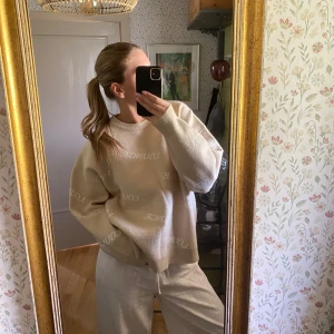 Beige stickad tröja från Lounge - Säljer en beige stickad tröja från Lounge med vit text över hela tröjan. Tröjan har rund halsringning och långa ärmar, perfekt för en avslappnad stil. Supermjuk och skön att ha på sig.