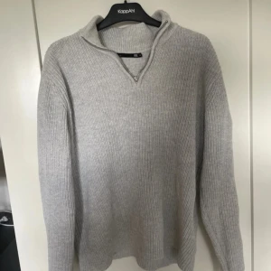 Ljusgrå stickad tröja med dragkedja från 157 - Säljer en ljusgrå stickad tröja från 157 i storlek M. Tröjan har en halv dragkedja vid halsen och är ribbstickad med lång ärm. Perfekt för lager-på-lager och enkel att matcha med det mesta.