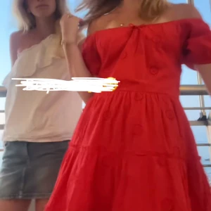 Röd offshoulder klänning med broderade detaljer - Superfin röd klänning med offshoulder-modell och korta puffärmar. Klänningen har broderade blommor, volanger och en liten rosett framtill.  lätt passform som passar perfekt till sommaren.❤️🌹