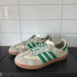 Adidas Wales bonner sneakers  - Säljer ett par Adidas Banner sneakers i vitt och grönt med klassiska tre ränder på sidan. Skorna har beige mockadetaljer, gröna och vita snören samt gummisula. Perfekta för dig som gillar retrostil och sportig look. Dom är använda en del men har fortfarande mycket kvar att ge efter en tvätt.