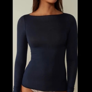 Mörkblå långärmad topp - En stilren mörkblå långärmad topp med tight passform och rund halsringning. Perfekt att styla till både jeans och kjol för en enkel men snygg look.