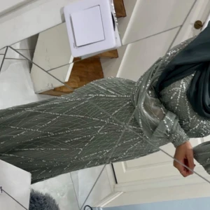 Ljusgrön glittrig långklänning från Maryisa - Elegant ljusgrön långklänning från Maryisa med glittrigt mönster och transparenta långa ärmar. Klänningen har en figurnära passform upptill och faller snyggt längs kroppen. Perfekt för speciella tillfällen. Köpt från Zalando. Klänningen har använts en gång i några få timmar. Storlek 36 💚