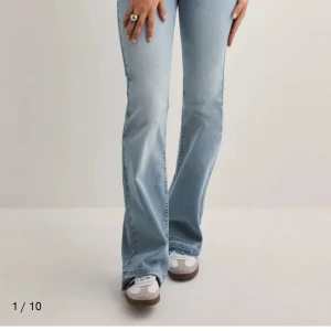 Ljusblå bootcut jeans Nelly  - Säljer ett par ljusblå bootcut jeans med klassisk femficksdesign och normal passform. Jeansen har hög midja och är tillverkade i mjukt denimtyg. Perfekta för dig som gillar en retroinspirerad look.