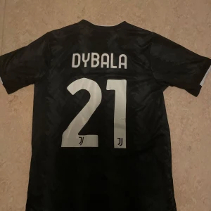 Juventus fotbollströja  - Snygg svart Juventus fotbollströja från Adidas med Dybala 21 på ryggen. 