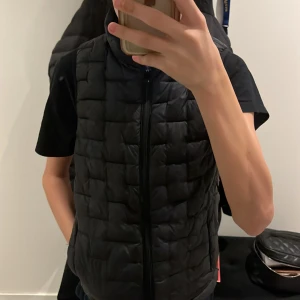 Svart quiltad dunväst från Everest - Säljer en svart quiltad dunväst från Everest. Västen har en dragkedja framtill och är perfekt för kyligare dagar. Den är stilren och lätt att matcha med olika outfits.