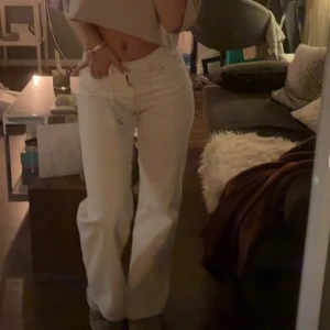Vita jeans - sommar25 - Snygga vita jeans med medel hög midja och bootcut-stil. Perfekta för en trendig look. De har knappar framtill och en klassisk femficksdesign. Använda 2 gånger!