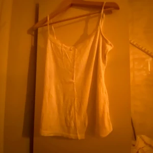 Vit linnetopp - Säljer en enkel och stilren vit linnetopp med smala axelband. Perfekt för varma dagar eller som ett basplagg i garderoben.