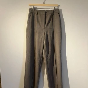 Beige kostymbyxor från NA-KD - Snygga beige kostymbyxor från NA-KD i storlek 38. Byxorna har en klassisk design med raka ben och hög midja. Perfekta för en stilren look.