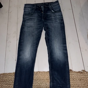 Blå jeans från Jack & Jones - Snygga blå jeans från Jack & Jones med en loose fit. Perfekta för en avslappnad stil.         Knappgylf.