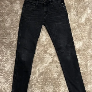 Replay Anbass - Snygga svarta  jeansbyxor från Replay med en slim passform. Byxorna har en klassisk femficksdesign och en diskret logga på bakfickan. Perfekta för en stilren look. L. 30