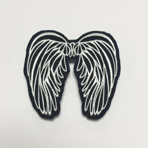 Mörk blått och vitt tygmärke med vingar för- mörk blåa jeans - Unikt tygmärke i form av vita vingar på svart bakgrund. Perfekt för att sätta på jackor, väskor eller jeans för en personlig touch. Broderad design som ger en cool och stilren look.