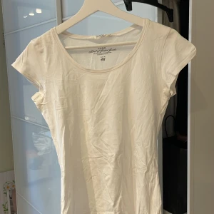 Vit t-shirt från H&M - Säljer en klassisk vit t-shirt från H&M. Den har en rund halsringning och korta ärmar, perfekt för en enkel och stilren look. Passar bra till både jeans och kjol.