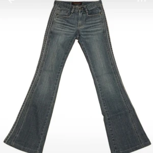 Låga blå bootcut jeans med broderad detalj - Snygga blå bootcut jeans med unik broderad detalj längs sidorna. Köpta på vinted, men lite korta på mig som är 173cm så säljer vidare. Nytt skick. 
