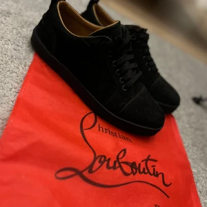 Svarta Christian Louboutin - Snygga svarta sneakers från Christian Louboutin. Skorna har en stilren design med snörning och är tillverkade i mocka. Perfekta för den som vill ha en touch av lyx i vardagen. Undersidan är bara smutsig har använt skorna två gånger men inte tvättat dom. Säljer dom på grund av att jag ej har den stil längre. Pris kan diskuteras, Hör av dig om du är intresserad😁