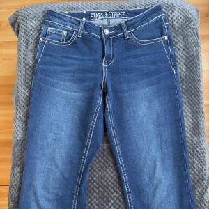 Blå jeans från Stars & Stripes - Snygga blå jeans från Stars & Stripes med dekorativa sömmar och broderier på bakfickan. Enbart använda 1 gång. Så i väldigt bra skick. Storlek 29(M)väldigt stretchiga.