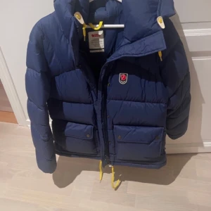 Blå dunjacka från Fjällräven - Säljer en snygg blå dunjacka från Fjällräven, säljer endast för den inte kommit till användning då den är för stor så den är nästan aldrig använd. Pris går att diskuteras vid snabb affär 
