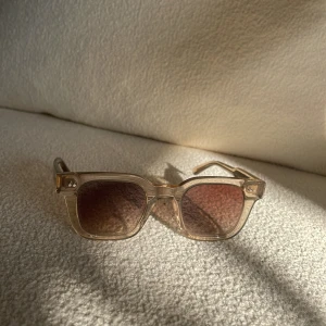 Chimi Solglasögon  - Chimi glasögon. Snygga solglasögon med transparent båge och fyrkantig form. Glasen har en lätt toning som ger en cool look. Perfekta för soliga dagar och en stilren accessoar till din outfit. 