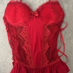 Röd spets korsett med snörning - Snygg röd korsett med spetsdetaljer och snörning på sidorna. Den har en vacker broderad design och en liten rosett framtill. Perfekt för en speciell kväll! Funkar både som S och M men helst för de med kupor större än 75a-b. Pris kan diskuteras!💕