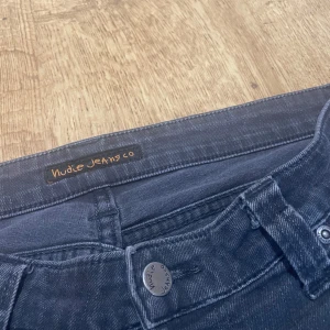 Svarta jeans från Nudie Jeans Co - Snygga svarta jeans från Nudie Jeans Co med en klassisk femficksdesign. De har en knappgylf och är tillverkade i ett slitstarkt denimtyg. Perfekta för en stilren look. Storlek w33 l 34 men är mindre i storleken