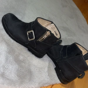 Svarta boots urban project  - Snygga svarta boots i skinn med dragkedja och ett dekorativt spänne på sidan. Perfekta för en stilren look och passar bra till både jeans och klänning.