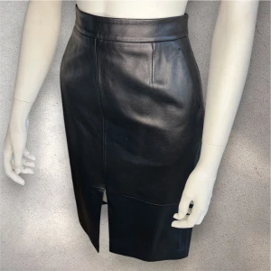 Svart skinnkjol med slits - Snygg svart skinnkjol Stockh LM med en stilren design och slits framtill. Kjolen har en tight passform och stängs med dragkedja bak. Perfekt för en chic look. #skinnkjol #stockhlm