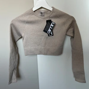 Beige ribbad croppad tröja från Aimn - Säljer en beige ribbad croppad tröja från Aim'n. Tröjan har långa ärmar och ett mjukt och stretchigt material. Perfekt för träning eller till vardags.