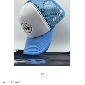 Blå och vit keps från All Cap One - Snygg keps i blått och vitt från All Cap One. Kepsen har ett broderat märke framtill och ett nätmaterial på baksidan för extra ventilation. Perfekt för soliga dagar!