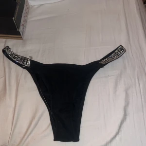Svarta bikini trosor från Victoria's Secret - Snygg underdel från Victoria's Secret med glittriga detaljer på sidorna. . Den har en elegant design med en tight passform.