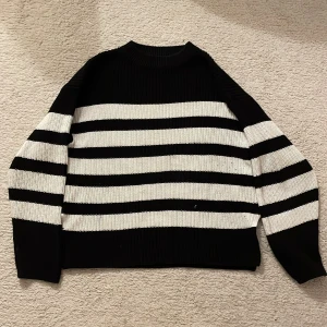 Svart och vit randig tröja från Gina Tricot - Säljer en snygg svart och vit randig tröja från Gina Tricot. Tröjan är stickad och har långa ärmar, perfekt för en stilren look. Den är i storlek 146/152 och passar bra för en snygg look