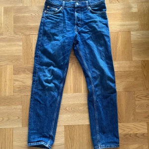 Blå jeans från Weekday - Snygga blå jeans från Weekday med en klassisk femficksdesign. De har en normal passform och är tillverkade i slitstarkt denim. Perfekta för en avslappnad stil. Barrel modell.